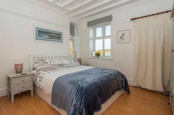 Bright bedroom with a double bed, bedside tables, and large windows.