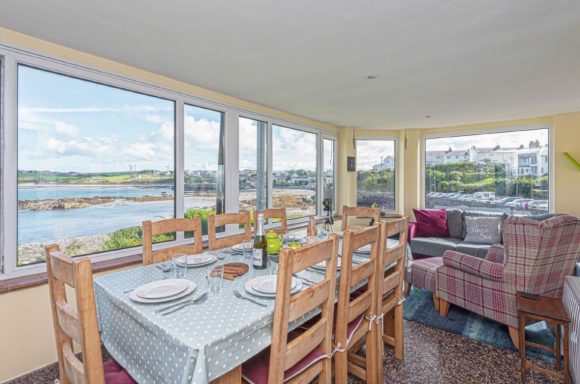 Bright dining area with large windows overlooking a scenic waterfront view.