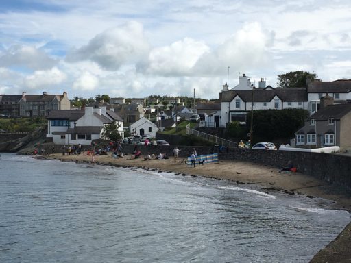 Coastal village with sandy beach, houses, and cloudy sky.