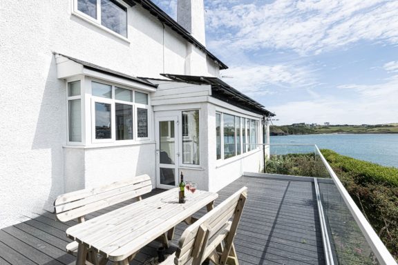 Coastal house with a patio dining area, overlooking a tranquil water view.