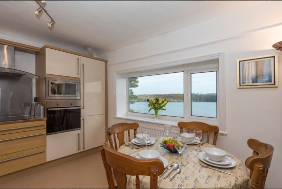 Bright kitchen with a dining table set and a view of the water through a window.
