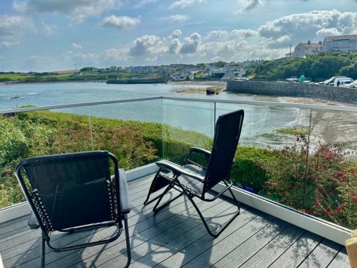 Two black chairs overlooking a serene water view with distant hills and clouds.