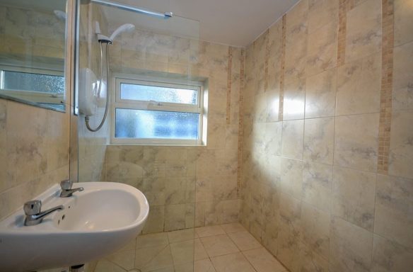 Bright bathroom featuring a sink, shower, and marble-like wall tiles.