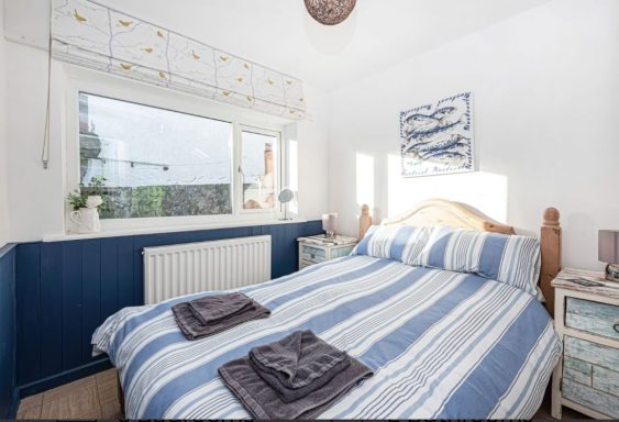 Cozy bedroom with blue striped bedding and two neatly folded towels on the bed.