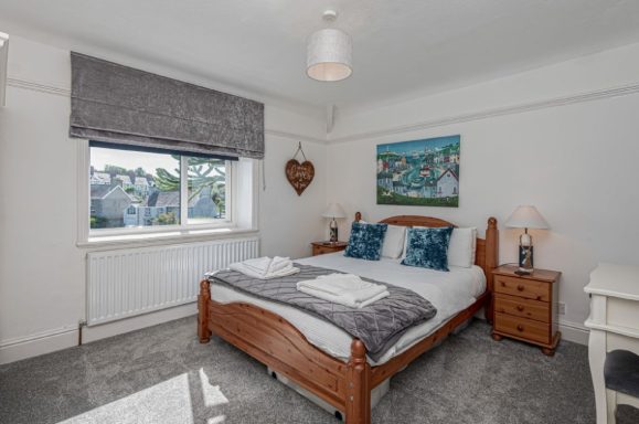 A modern bedroom featuring a double bed, bedside tables, and a window with natural light.