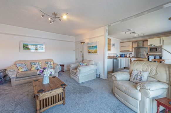 Cosy living area with beige sofas, a wooden coffee table, and an open kitchen.