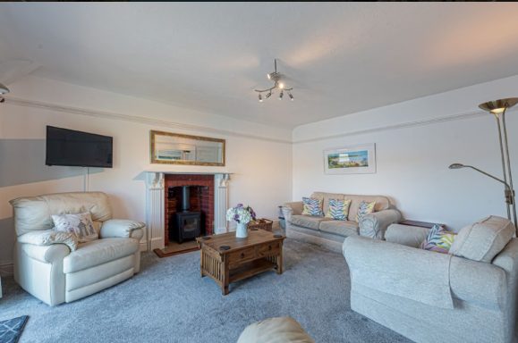 A bright living room with beige furniture, a coffee table, and a fireplace.