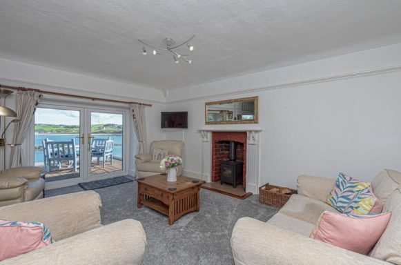 Cozy living room with a view of the water, comfortable sofas, and a fireplace.